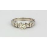 An 18ct white gold ring set with a brilliant cut diamond and baguette cut diamond set shoulders, (