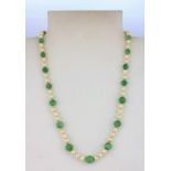 A polished jade and faux pearl necklace on a 9ct yellow gold clasp, L. 46cm.