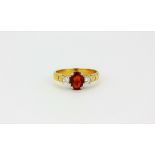 A yellow metal (tested 18ct gold) ring set with an oval cut ruby and diamond set shoulders, (M.5).