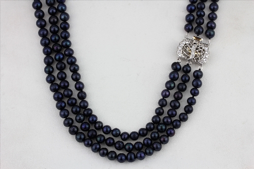 A triple row blue /black cultured pearl necklace on a stone set white metal clasp, L. 44cm, together