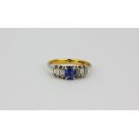 An 18ct yellow and white gold ring set with an step cut sapphire and baguette cut diamonds, (N).