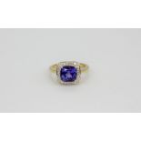 An 18ct yellow gold (stamped 750) ring set with a cushion cut tanzanite surrounded by diamonds,