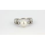 A 9ct white gold pearl set ring with diamond set shoulders, (N.5).