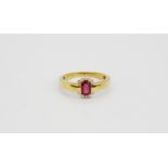 An 18ct yellow gold (stamped 750) ring set with an oval cut ruby surrounded by brilliant cut