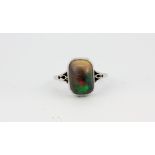 A white metal (tested platinum) ring set with a cabochon cut black opal, (M.5).