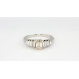 An 18ct white gold (stamped 750) ring set with an emerald cut diamond and baguette cut graduated