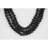 A three row necklace of blue black cultured pearls with a pair of matching earrings, pearl size.