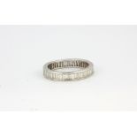 A white metal (tested 18ct gold) full eternity ring set with baguette cut diamonds, (R).