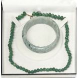 A boxed single strand necklace of 7.5mm jade beads, L. 46cm, together with a jade bangle.