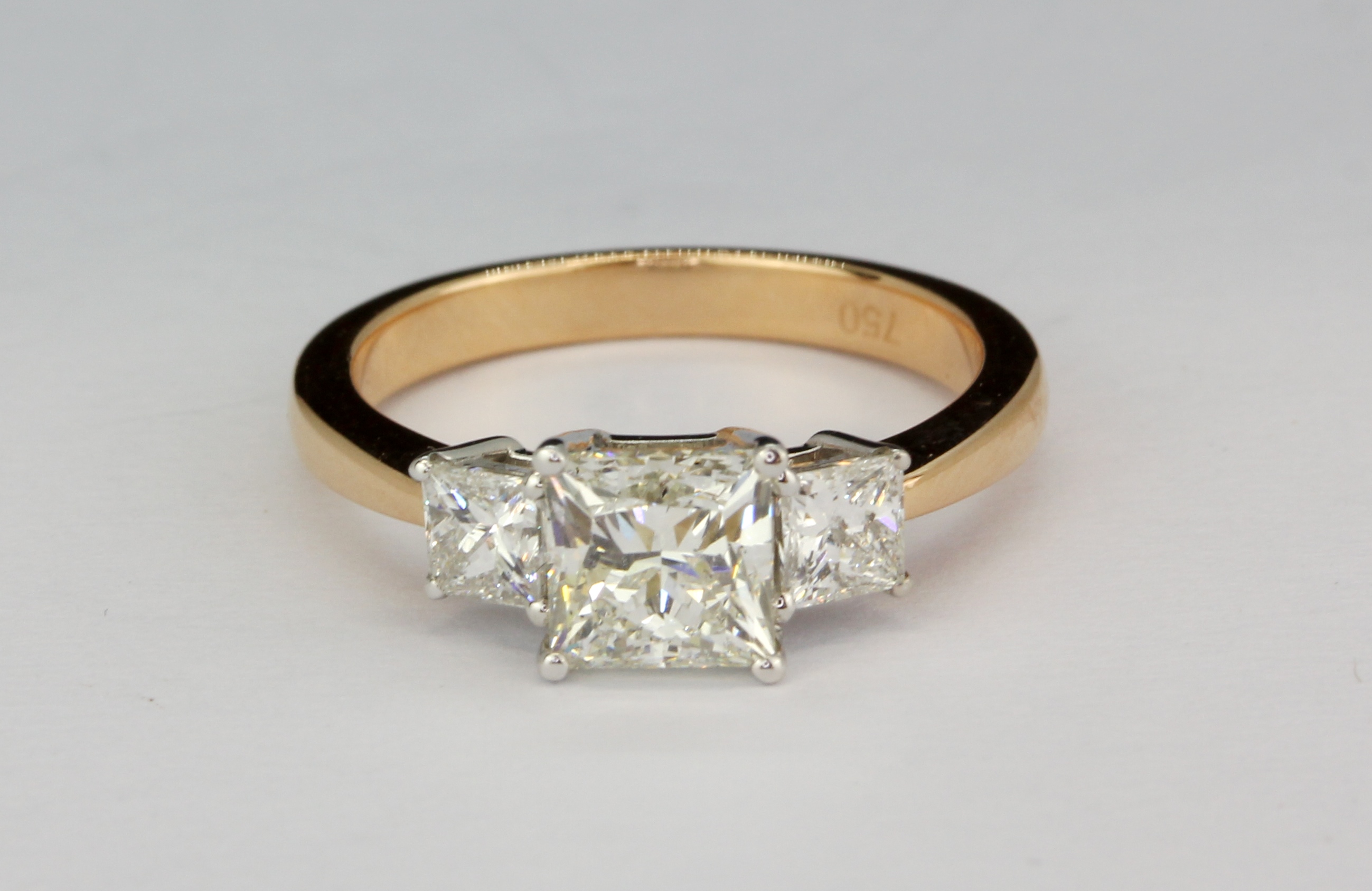 A rose metal (tested 18ct gold) trilogy ring set with three princess cut diamonds, approx. 1.37ct