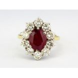 An 18ct yellow gold cluster ring set with an oval cut ruby surrounded by brilliant cut diamonds,