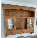 A wall mounted glazed pine kitchen cabinet with central plate rack, W. 120. H. 107.