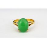 A 14ct yellow gold (stamped 14k) ring set with a cabochon cut nephrite jade, (L).