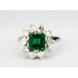 An 18ct white gold (stamped 750) ring set with an emerald cut emerald and fancy step cut diamonds,