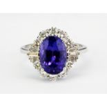 An 18ct white gold cluster ring set with an oval cut tanzanite surrounded by brilliant cut diamonds,