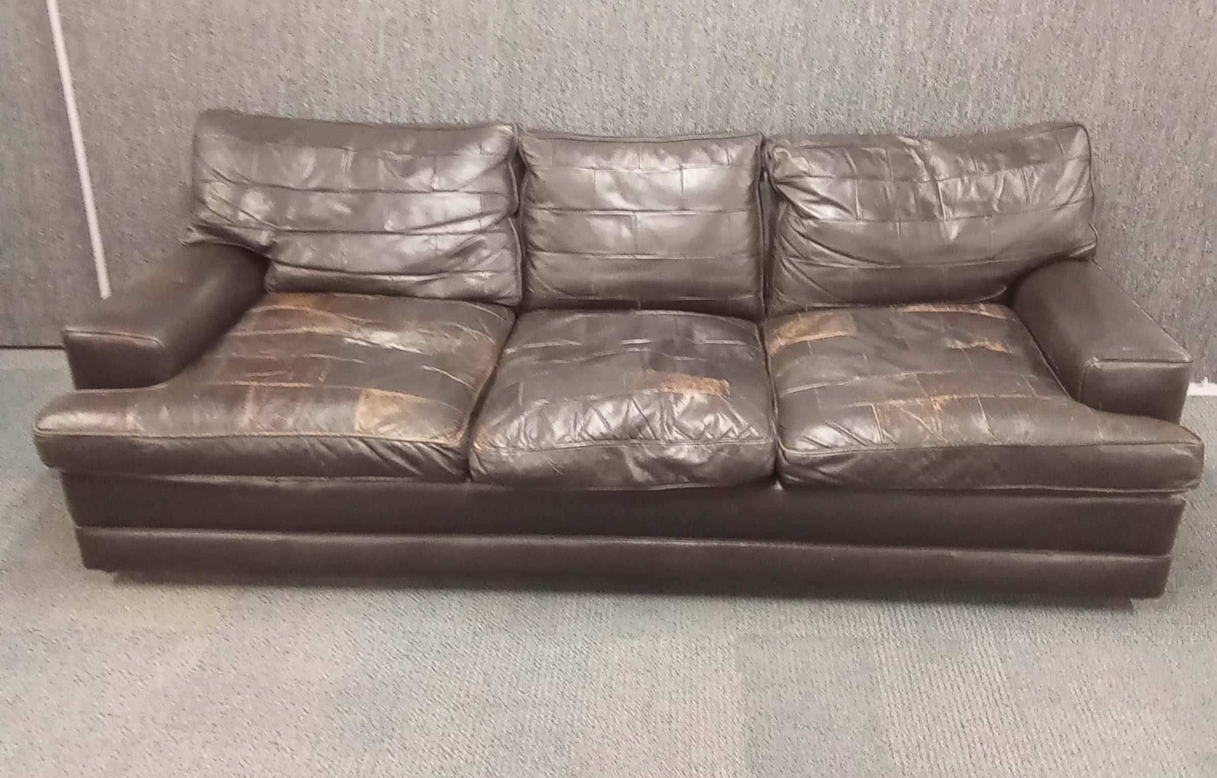 A 1970's brown leather three piece lounge suite with reversable patchwork and plain seat covers,