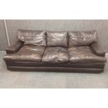A 1970's brown leather three piece lounge suite with reversable patchwork and plain seat covers,