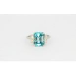 A white metal (tested high carat gold) ring set with an emerald cut natural blue zircon and