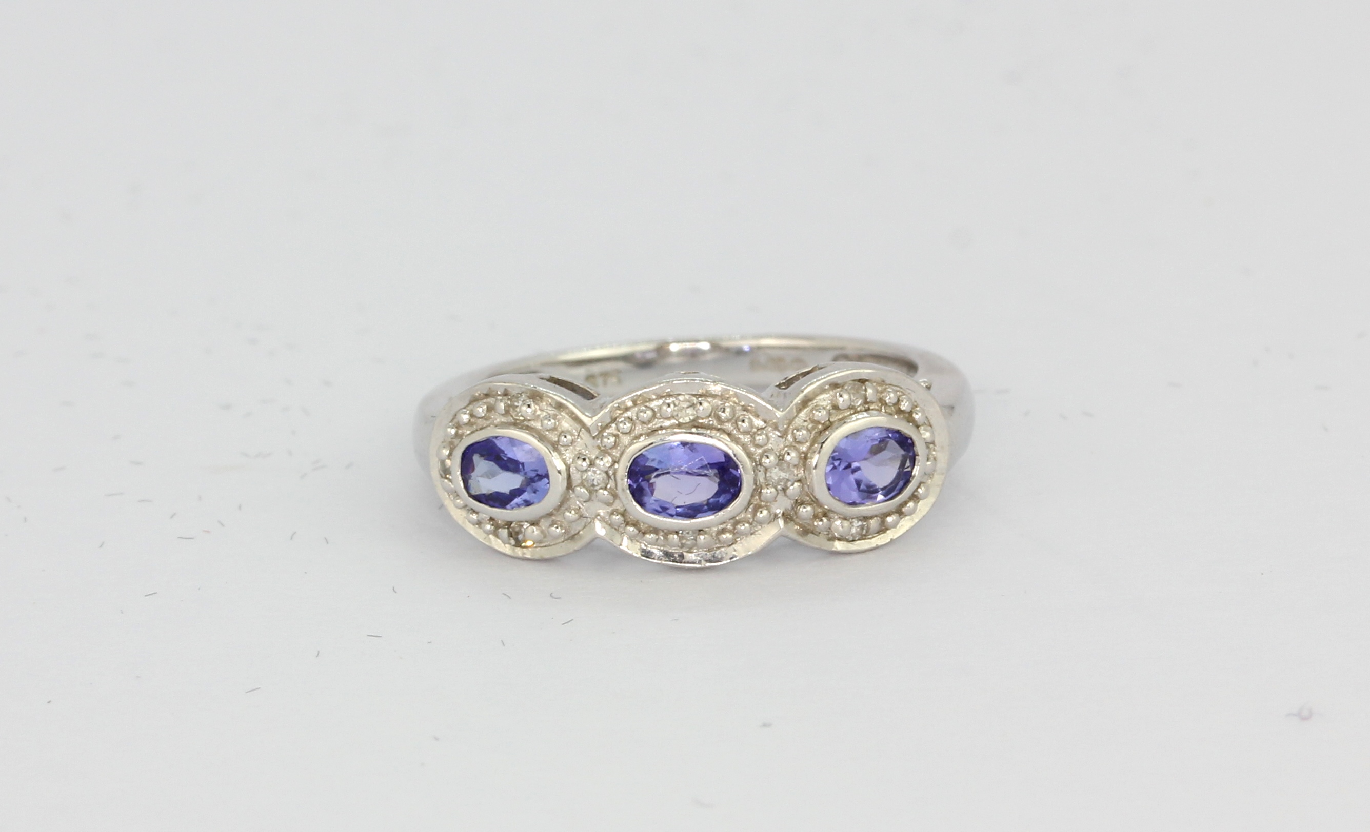 A 9ct white gold tanzanite and diamond set triple cluster ring, (L).