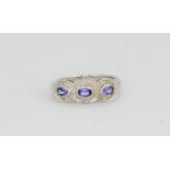 A 9ct white gold tanzanite and diamond set triple cluster ring, (L).