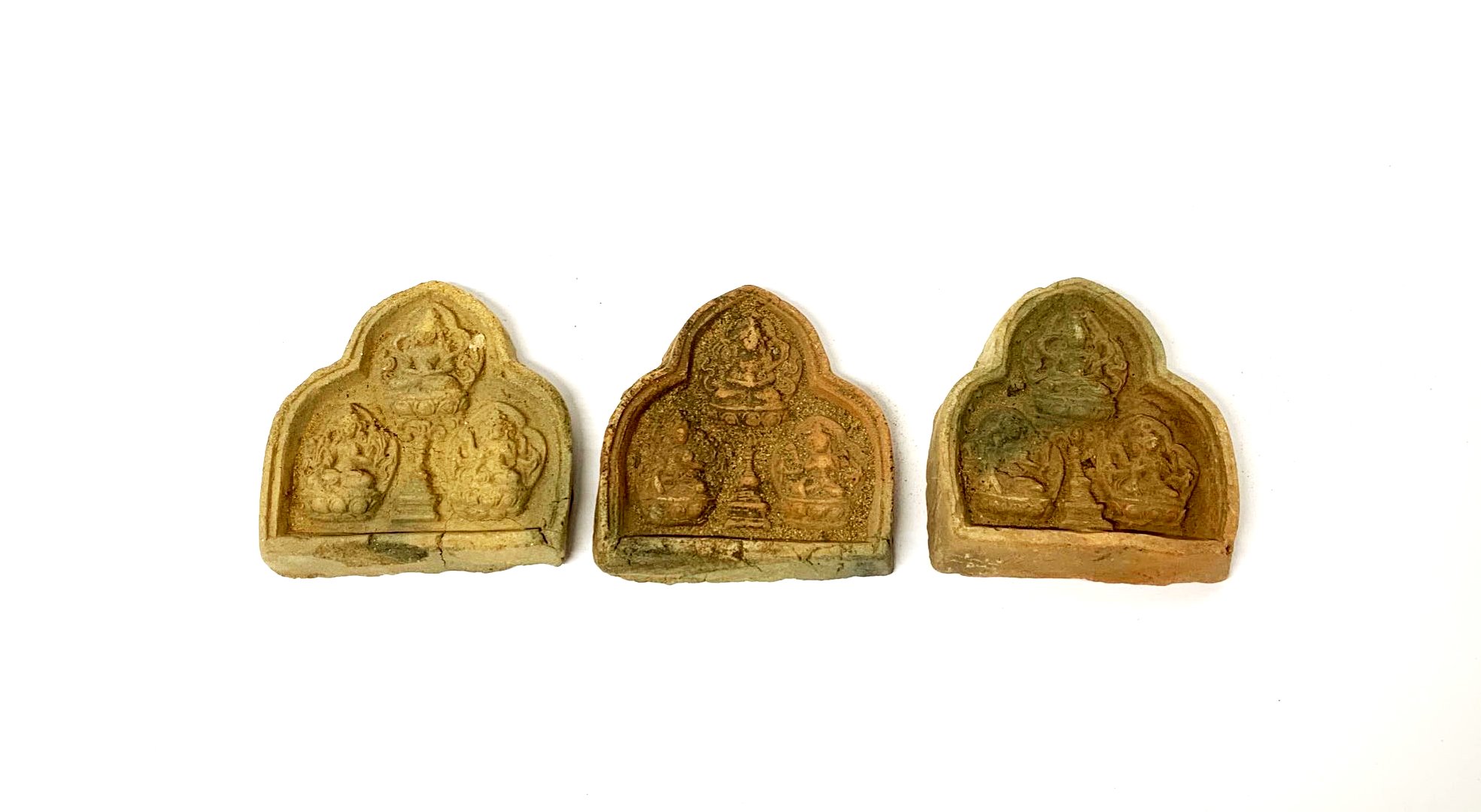 Three 19th/ early 20th Century Tibetan sun baked clay Buddhist devotional tablets, H. 5cm.