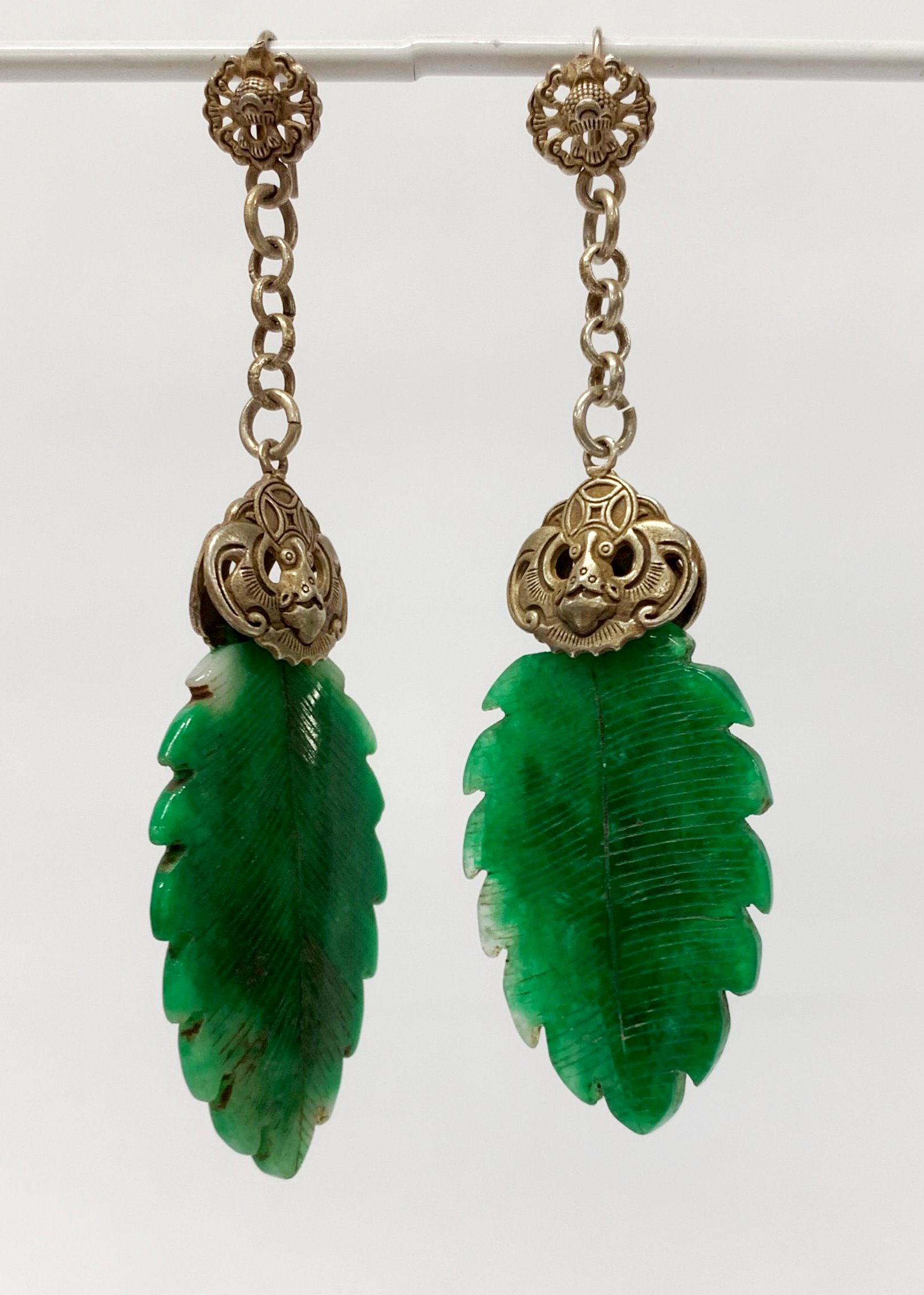 A pair of unusual Chinese white metal mounted carved jade earrings, L. 9.5cm.
