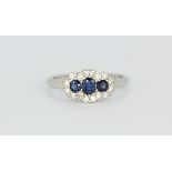 An 18ct white gold triple cluster ring set with oval cut sapphires and diamonds, (L).