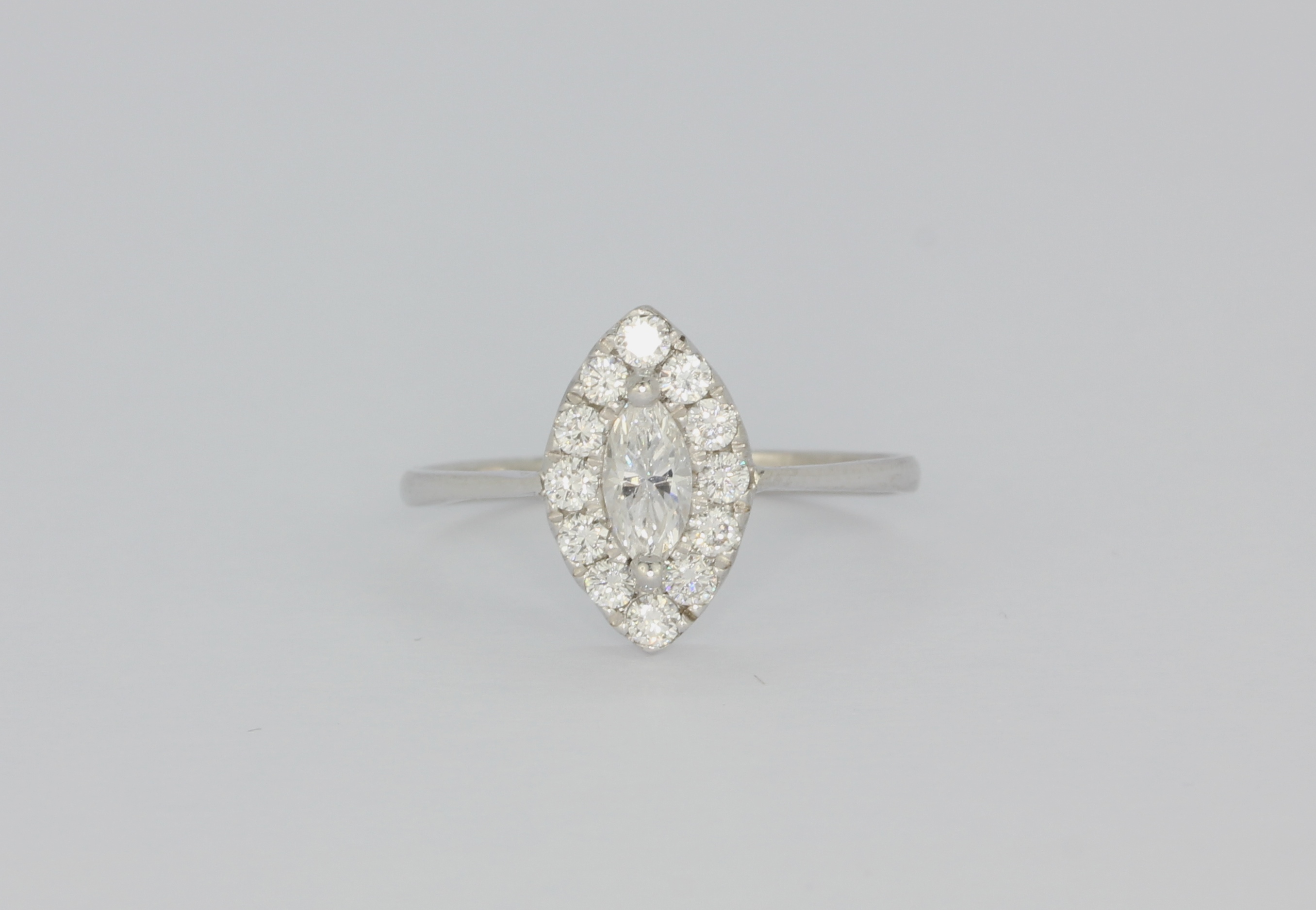 A white metal (tested 18ct gold) ring set with marquise and brilliant cut diamonds, (N).