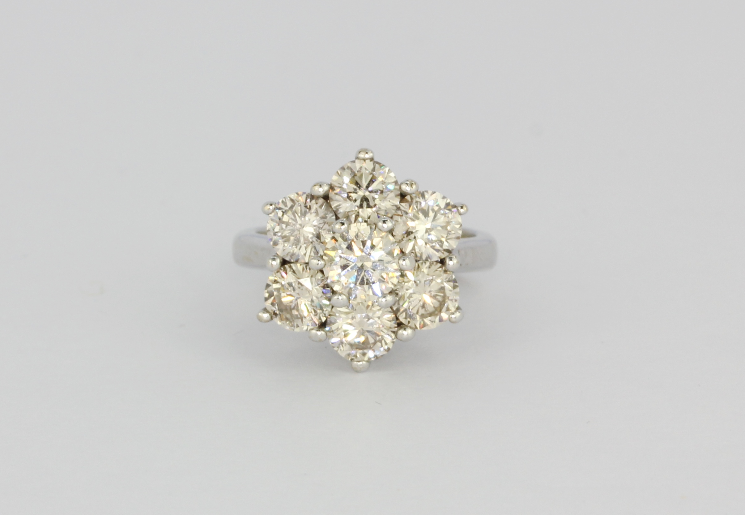 An 18ct white gold (stamped 750) cluster ring set with brilliant cut diamonds, approx. 3.15ct, (I).