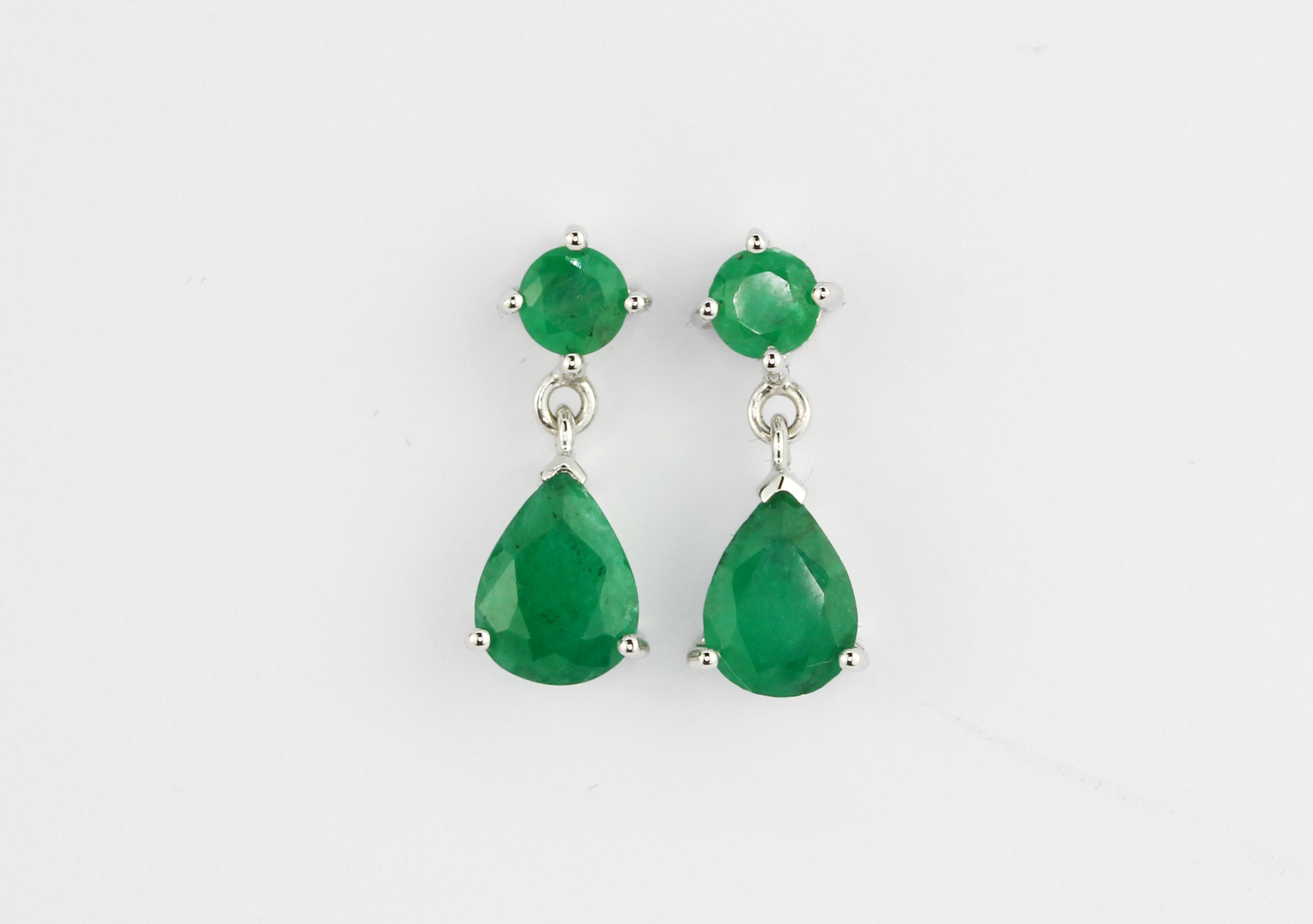 A pair of 14ct white gold drop earrings set with round and pear cut emeralds, L. 1.6cm.