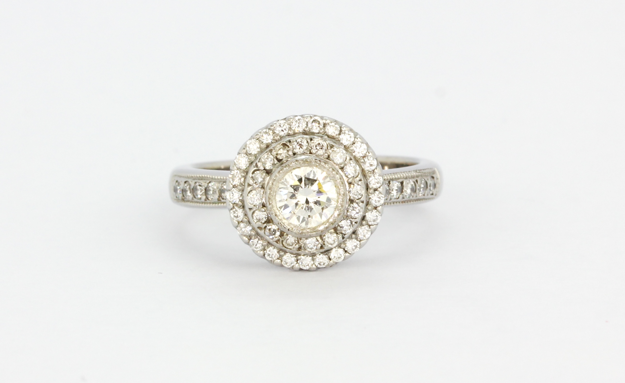 An 18ct white gold halo ring set with a brilliant cut centre diamond surrounded by brilliant cut