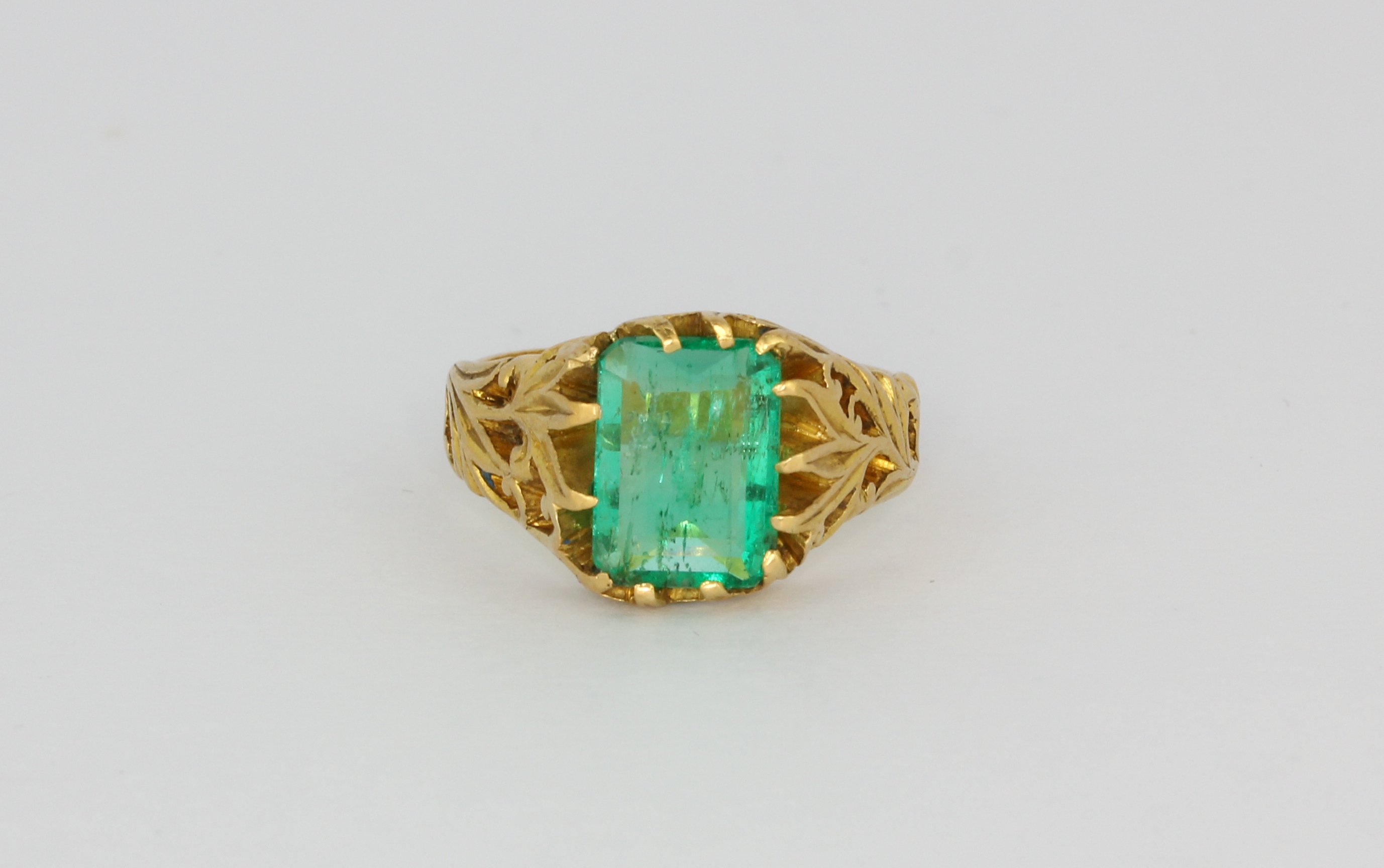A yellow metal (tested high carat gold) ring set with an emerald cut Columbian emerald, with a GCS