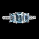 A 925 silver ring set with three emerald cut blue topaz and white stone set shoulders.