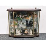 A wall mounted glass case of collectors cat figures.