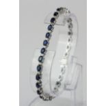 A 14ct white gold (stamped 14k) line bracelet set with oval cut sapphires and brilliant cut
