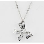 An 18ct white gold bow shaped pendant set with baguette cut diamonds, L. 2cm.