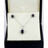 A suite of matching 9ct white gold pendant and chain and matching pair of earrings, set with oval