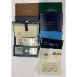 A collection of 11 silver coin stamp sets and one Wedgwood set.