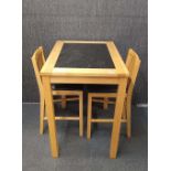 A contemporary marble topped high level breakfast table and two bar stool style chairs.