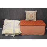 An upholstered ottoman, a quilted double bed cover and tapestry cushion.