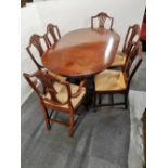 A mahogany veneered dining table and a set of six lyre and wheatsheaf backed chairs.