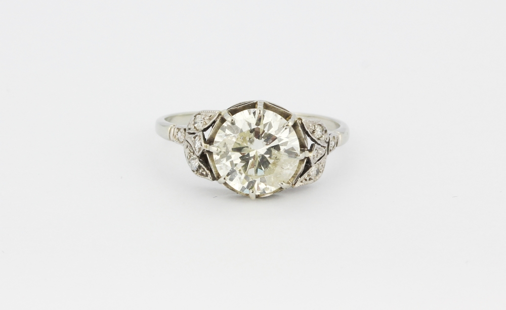 A white metal (tested high carat gold) ring set with a brilliant cut diamond and diamond set