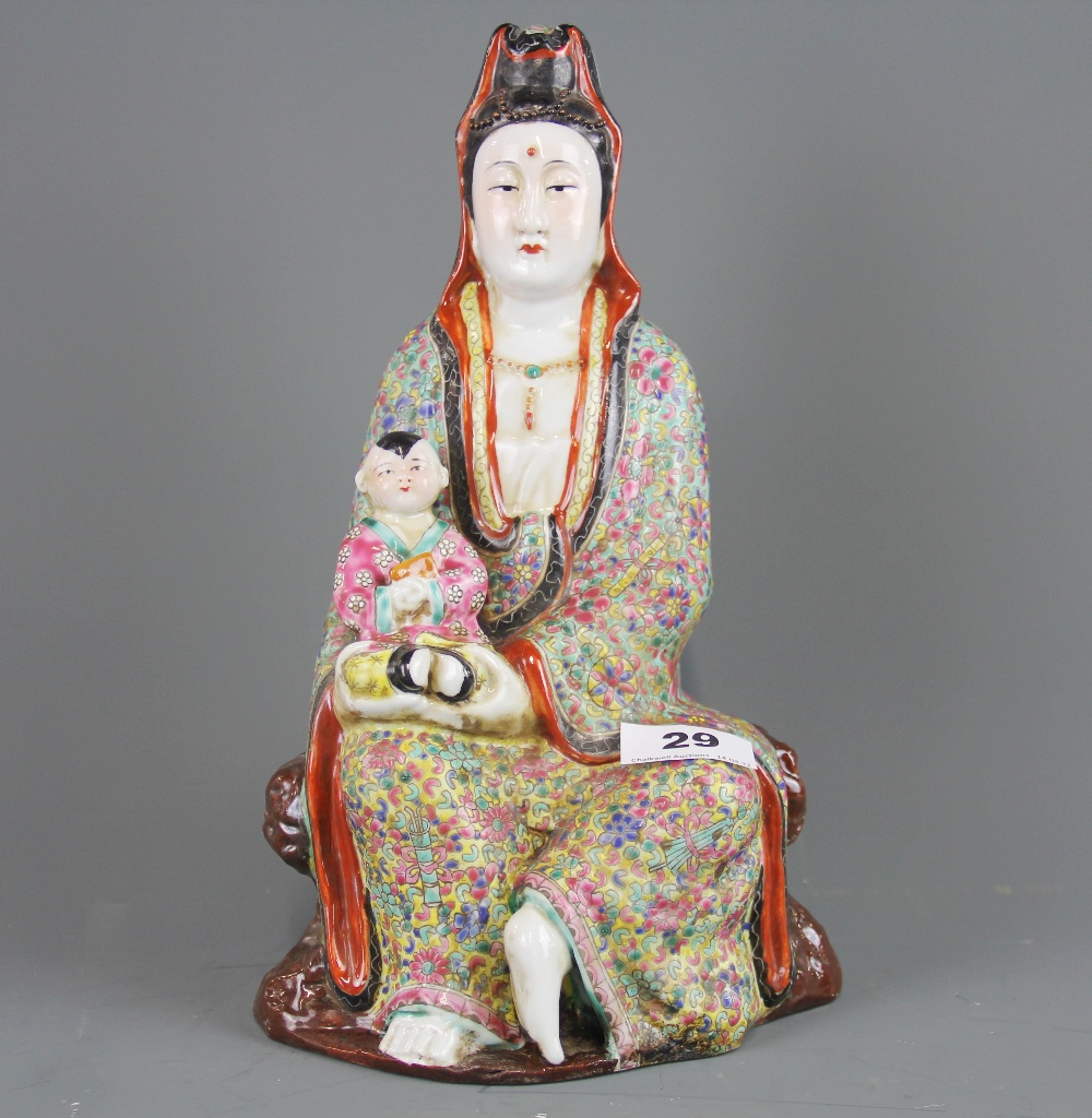 A Chinese hand enamelled porcelain figure of the goddess Guanyin holding a child, H. 29cm. Impressed