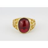 A 9ct yellow gold (stamped 9ct) ring set with an oval cabochon cut red stone, (U.5).