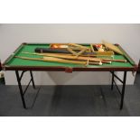 A table top snooker table with cues, scoreboard and balls.