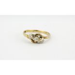 A 9ct yellow gold crossover ring set with three brilliant cut diamonds, (M).