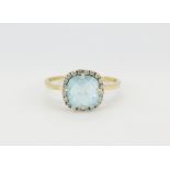 A 14ct yellow gold (marked ARPAS 585) ring set with a faceted cut blue topaz surrounded by white