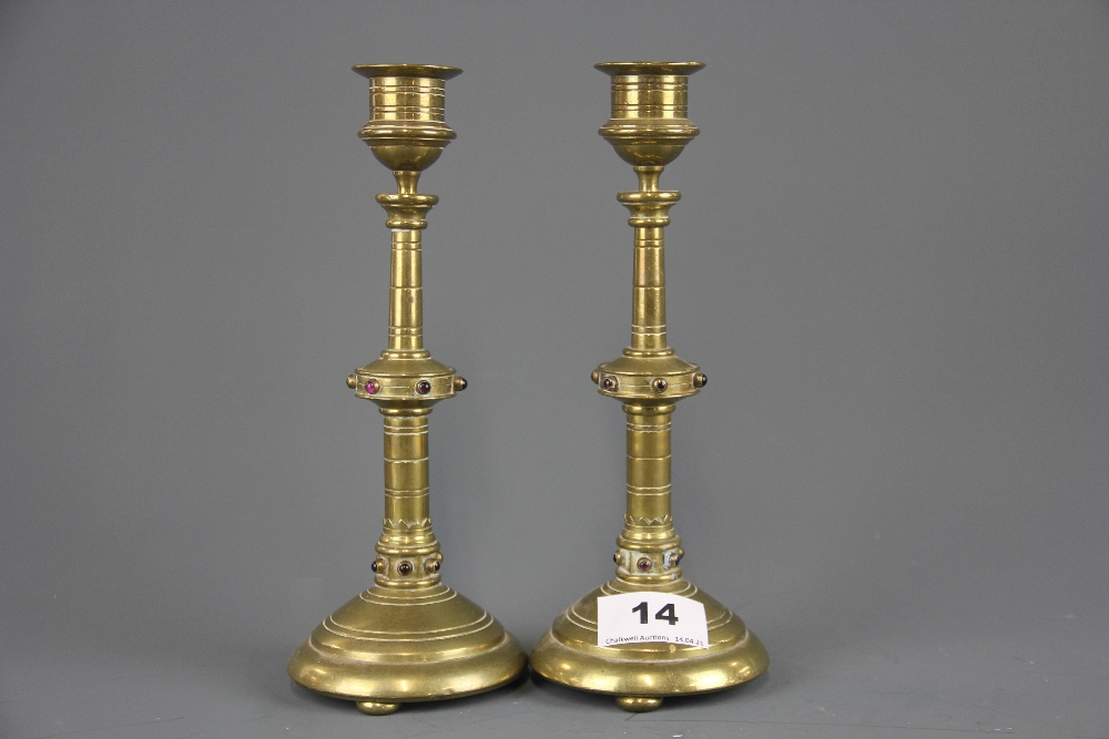 A pair of ecclesiastical style brass candlesticks inset with semi precious stones, H. 22cm.