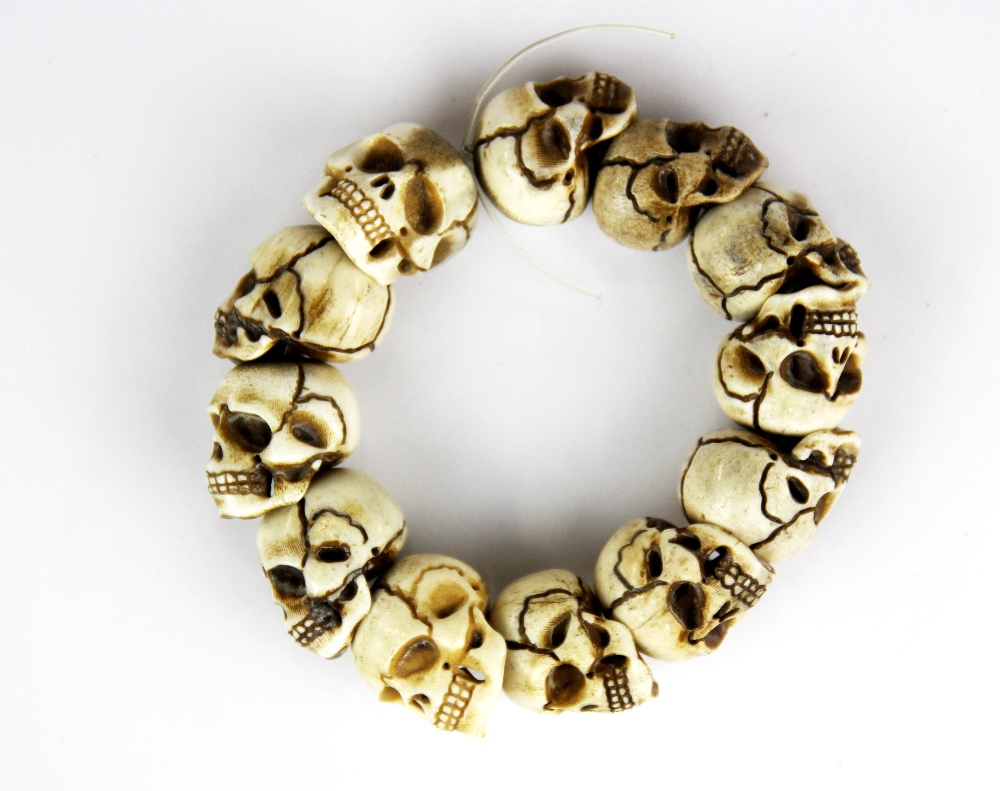 A group of 12 carved antler skulls threaded as a bracelet, skull size 2.5cm.