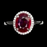 A 925 silver cluster ring set with an oval cut ruby surrounded by white stones, (P).